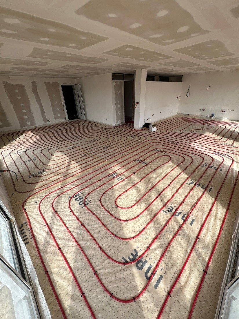 Tubes de plancher chauffant posés en serpentin dans une grande pièce