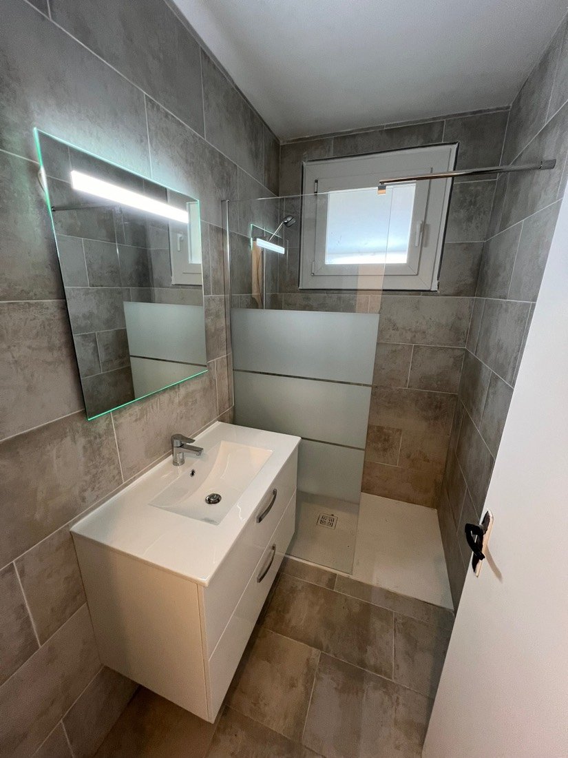 Salle d’eau avec meuble blanc et miroir lumineux