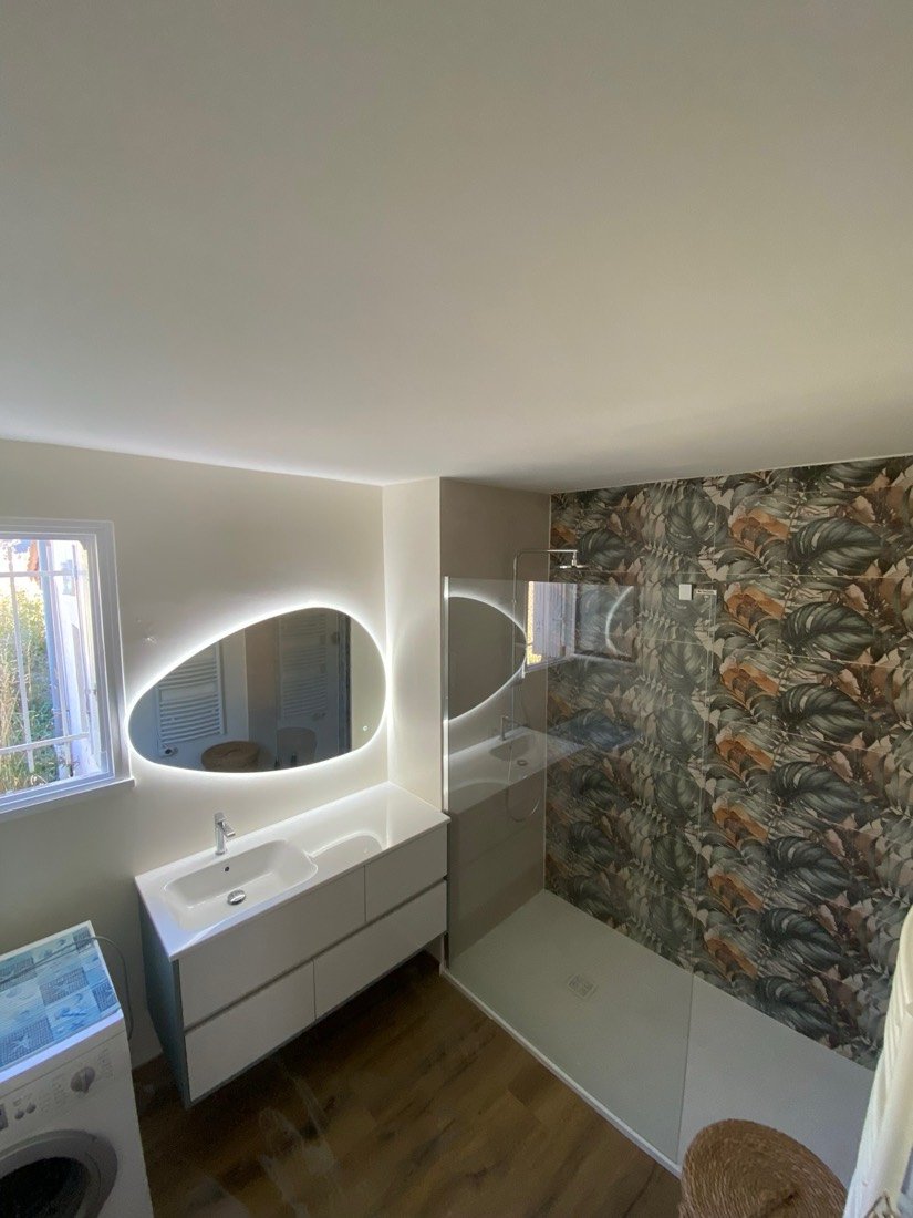 Salle de bain avec miroir lumineux et papier peint à feuillage
